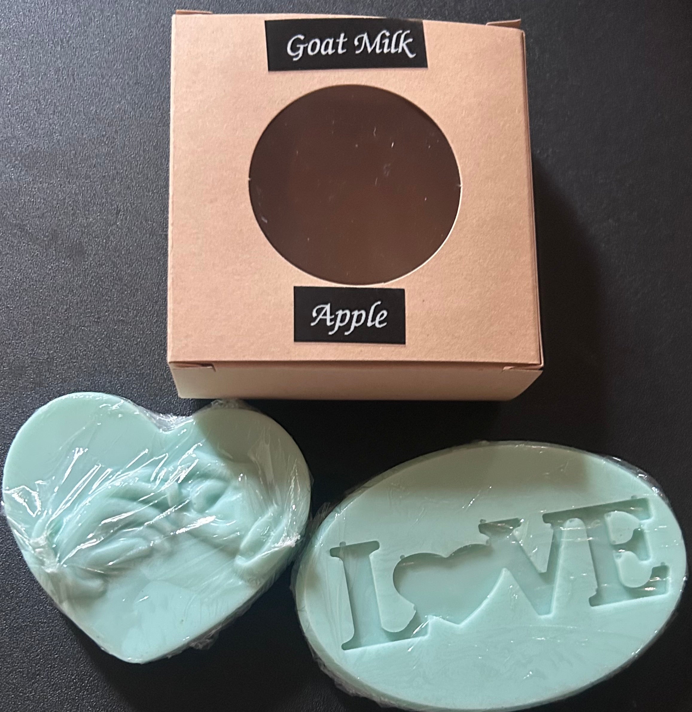 Two goat milk soaps, one heart-shaped and one oval with 'LOVE' engraving, - 'Goat Milk Apple'