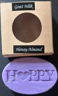 Purple soap bar with 'Happy' text ,'Goat Milk Honey Almond'.
