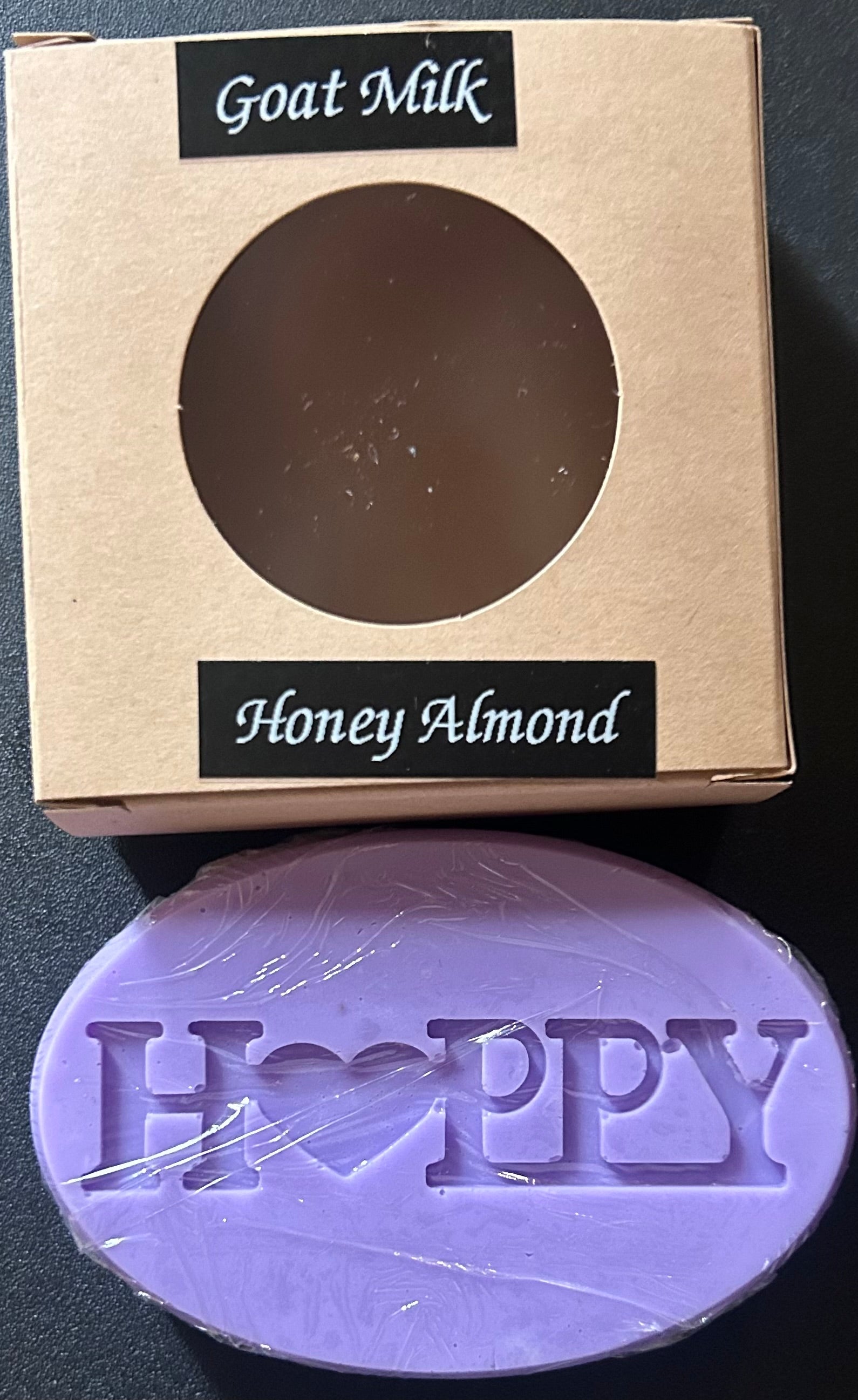 Purple soap bar with 'Happy' text ,'Goat Milk Honey Almond'.